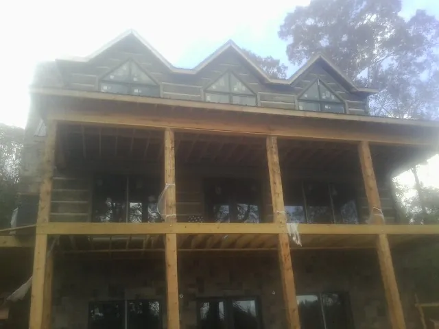 Dormers and porch framing on a large log home under construction — Roof Coating work by our crew in Devine