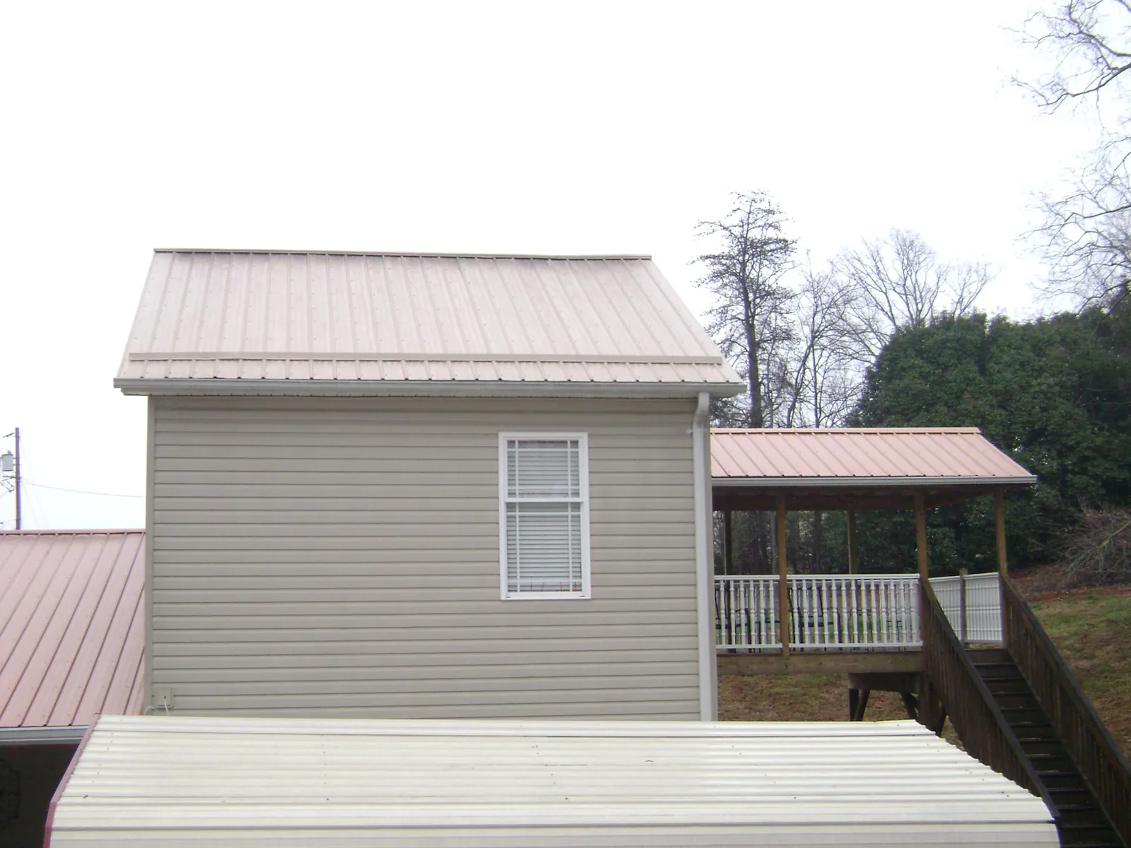 Tan metal roofs on a two story addition and attached porch, from a Roof Replacement job in Devine