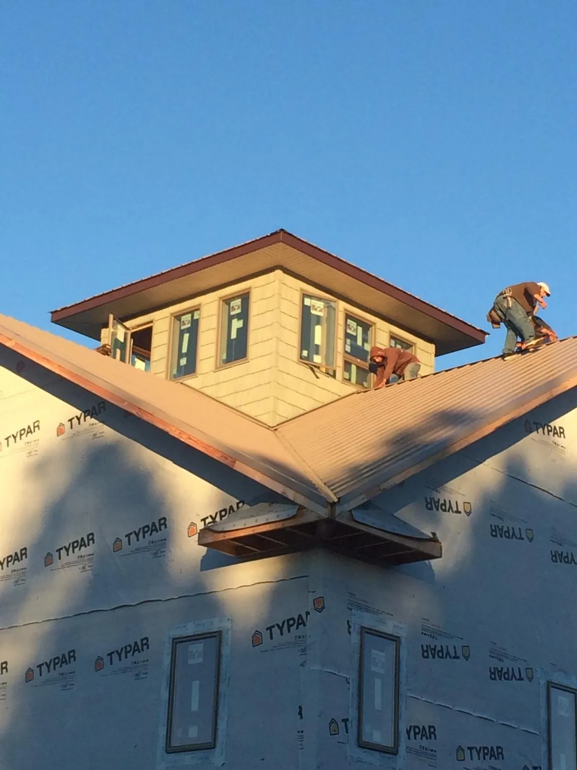 Roofers working around a rooftop cupola on a new metal roof at sunset — Roof Waterproofing in Devine by Roofing Brothers